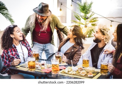 Multiracial Guys And Girls Drinking Beer Pints At Balcony Patio - Youth Social Gathering Life Style Concept On Happy People Enjoying Hangout Time Together Out Doors - Vivid Filter With Bulb Light Halo