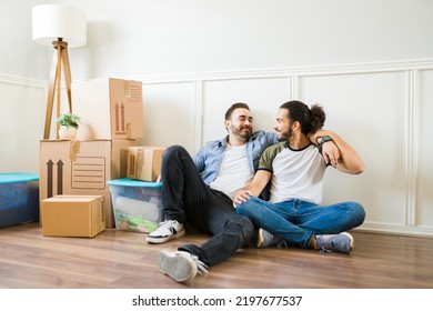 Multiracial handsome gay couple embracing after bringing the boxes to the new apartment while moving in together  - Powered by Shutterstock