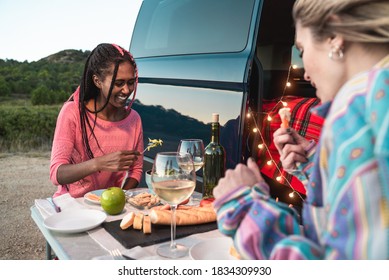 Multiracial happy friends celebrating and eating vegan food in front of camper van in park - Focus on black girl