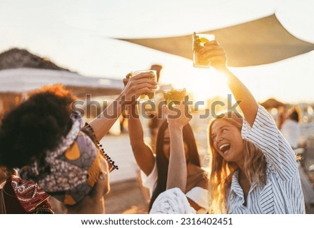 Multiracial happy friends cheering and drinking mojitos at beach party - Focus on left hand holding cocktail