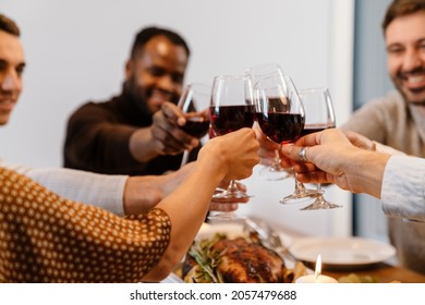 Multiracial Happy Friends Drinking Wine During Thanksgiving Dinner At Home