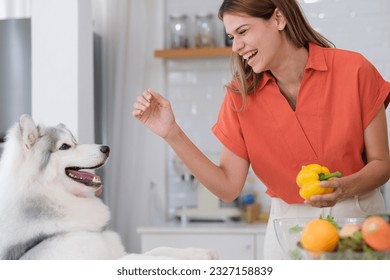 Multiracial Lesbian couple enjoy cooking salad with her dog in kitchen - Powered by Shutterstock