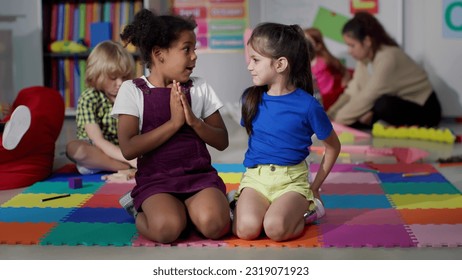 Multiracial little girls tell secrets sitting on floor in kindergarten. Adorable preschool African-American and caucasian girls sitting together in playroom share secrets - Powered by Shutterstock