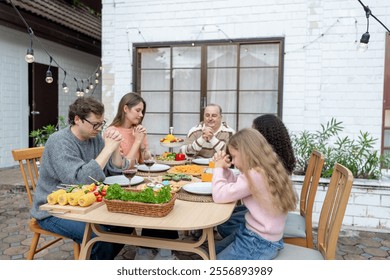 Multiracial lovely family saying a prayer before having dinner party. Attractive family members closing eyes and making a wish, celebrate holiday Thanksgiving xmas on dining table outdoors at home. - Powered by Shutterstock