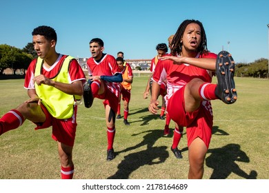 Multiracial male athletes stretching legs while standing on playground against clear sky, copy space. Unaltered, soccer, player, sport, teamwork, competition, exercising, training and fitness. - Powered by Shutterstock