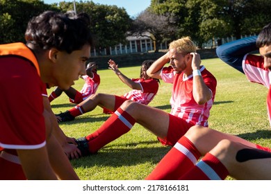 Multiracial male players assisting teammates in doing crunches on grassy field at playground. Helping, unaltered, soccer, sport, teamwork, competition, exercising, training and fitness concept. - Powered by Shutterstock