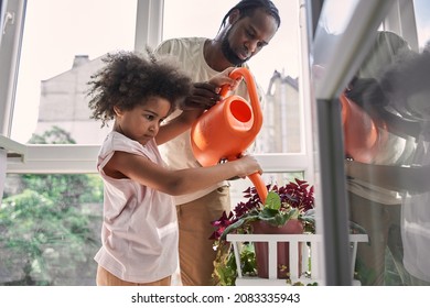 Multiracial man teaching his little daughter to taking care of the home flowers - Powered by Shutterstock