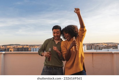 multiracial man and woman dancing together with beer on rooftop - Powered by Shutterstock