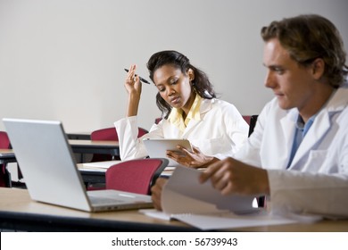 Multiracial Medical Students Wearing Lab Coats Studying In Classroom