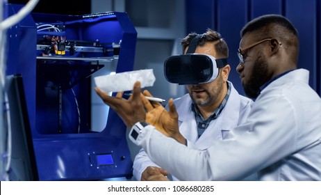 Multiracial Men In Medical Gowns Exploring 3d Scull Model In VR Glasses And Having Discussion.