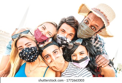 Multiracial milenial friends taking selfie smiling behind face masks - New normal summer friendship concept with young people having fun together - Warm bright backlight filter with tilted composition - Powered by Shutterstock