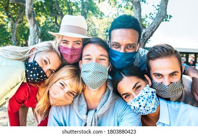 Multiracial Milenial Friends Taking Selfie With Closed Face Masks During Covid Second Wave Outbreak - New Normal Lifestyle Concept With Young People Having Fun Together - Bright Vivid Backlight Filter