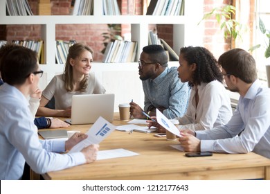Multiracial millennial colleagues brainstorm discussing startup ideas during briefing in boardroom, female CEO hold business meeting with diverse employees, negotiating analyzing report or stats