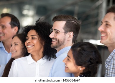 Multiracial Millennial Colleagues Stand In Row Smiling Posing For Group Picture, Excited Young Diverse People Gather Make Team Photo, Motivated For Shared Future Success. Business Vision Concept