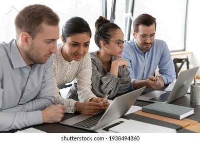 Multiracial Millennial Employees Involved In Project Development, Working In Small Groups On Laptops, Sitting Together At Desk In Office, Diverse Teammates Brainstorming Using Computer Applications.