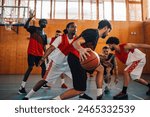 Multiracial muscular man playing basketball in a basketball court indoor. Diverse men dribbling the ball and playing together while practicing in a sports hall. Copy space.