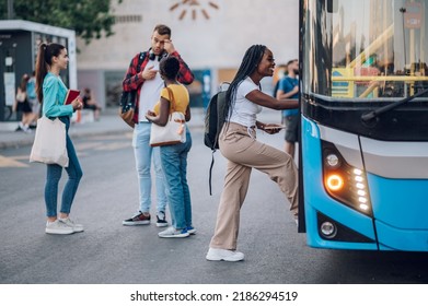 Multiracial passengers waiting at a bus stop and talking cheerfully. Focus on an african american woman entering the bus. Diverse tourists in new town. Best friends traveling together in a city.
