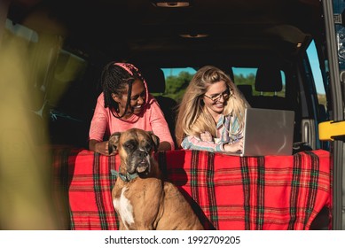 Multiracial people with dog traveling together retro mini van transport - Digital nomad concept working at laptop computer - Focus on african girl face