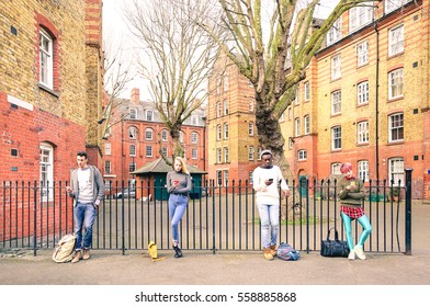 Multiracial people group and urban friends using smartphone near Shoreditch London - Technology addiction lifestyle concept with bored guys and girls texting on mobile smart phone - Warm retro filter