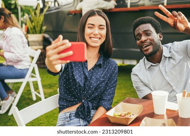 Multiracial people having fun doing selfie with mobile phone at food truck restaurant outdoor - Focus on african man face - Powered by Shutterstock