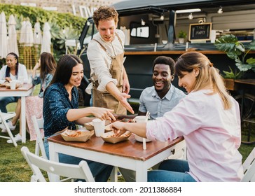 Multiracial people having fun eating at food truck outdoor - Focus on left girl face - Powered by Shutterstock