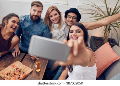 Multiracial People Having Fun At Party Taking A Selfie With Mobile Phone. Group Of Young Friends Sitting On Couch Taking Self Portrait With Smart Phone.