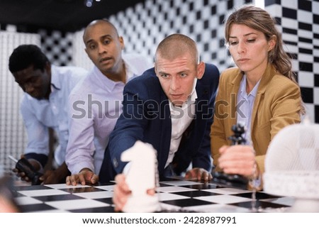 Multiracial people trying to find solution of conundrum in chess escape room
