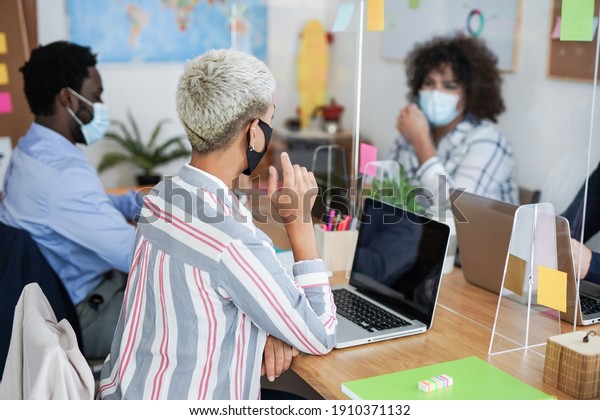 Multiracial people working in office with safety\
measures for coronavirus outbreak - Protective face mask and\
dividers for social\
distance