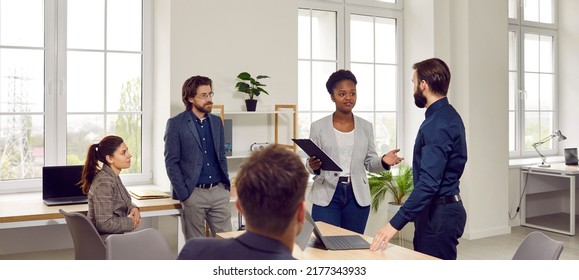 Multiracial people working in small startup or large company talking during business meeting solving organizational issues in spacious office around table. Inclusion and diversity in corporate culture