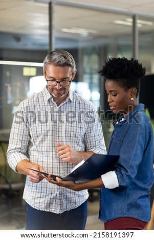 Multiracial professionals planning together while discussing over file at modern workplace. unaltered, business, teamwork and modern office concept.