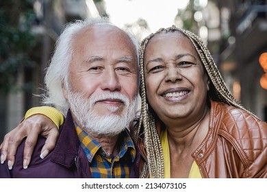 Multiracial senior couple looking at camera outdoor - Travel elderly people concept - Focus on african woman face - Powered by Shutterstock