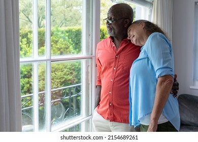 Multiracial senior couple looking through window while standing at home. unaltered, lifestyle, retirement, togetherness, contemplation. - Powered by Shutterstock