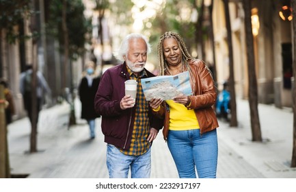 Multiracial senior couple searching a location in the map. Mature asian man with disposable coffee. - Powered by Shutterstock