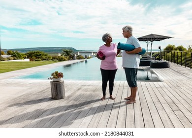 Multiracial Senior Friends With Exercise Mats Standing On Hardwood Floor Against Sky At Nursing Home. Sunlight, Swimming Pool, Unaltered, Togetherness, Support, Assisted Living, Retirement, Fitness.