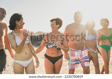 Multiracial senior friends having fun together during summer vacation - Elderly people walking on the beach