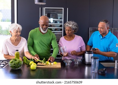 Multiracial senior friends making smoothie with granny smith apples and leaf vegetables in kitchen. Retirement home, unaltered, togetherness, support, assisted living and healthy food concept. - Powered by Shutterstock