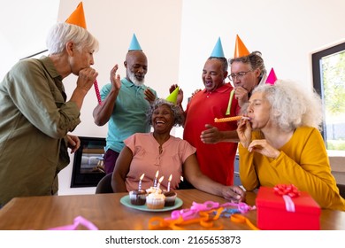 Multiracial senior friends singing and blowing party horns for senior woman in nursing home. Birthday, celebration, cupcake, enjoyment, unaltered, togetherness, support, assisted living, retirement. - Powered by Shutterstock