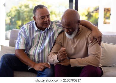 Multiracial senior man consoling male friend crying while sitting on sofa in nursing home. Sadness, togetherness, comfort, unaltered, emotional stress, support, assisted living, retirement concept. - Powered by Shutterstock