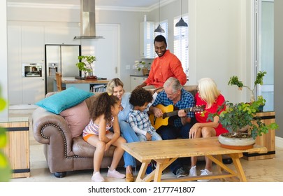 Multiracial senior man playing guitar while sitting with happy multigeneration family on sofa. Unaltered, family, togetherness, childhood, retirement, music, hobbies, lifestyle and home concept. - Powered by Shutterstock