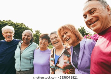 Multiracial senior people having fun hugging each other after sport workout at city park - Healthy lifestyle and joyful elderly lifestyle concept - Main focus on right woman face - Powered by Shutterstock