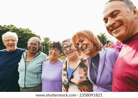 Multiracial senior people having fun hugging each other after sport workout at city park - Healthy lifestyle and joyful elderly lifestyle concept - Main focus on right woman face
