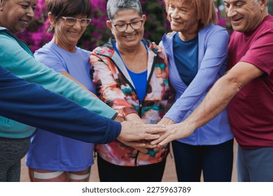 Multiracial senior people stacking hands after sport workout outdoor - Powered by Shutterstock
