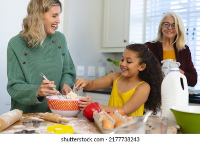 Multiracial senior woman looking at happy daughter and granddaughter mixing food in bowl in kitchen. Multigeneration, unaltered, togetherness, childhood, preparation, learning, lifestyle and home. - Powered by Shutterstock