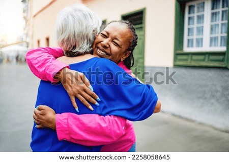 Multiracial senior women hugging each other - Elderly friendship and love concept - Soft focus on African female braids
