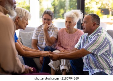 Multiracial seniors holding hands and comforting while sitting with friends in group therapy session. Sad, console, unaltered, emotional stress, together, support, assisted living, retirement home. - Powered by Shutterstock