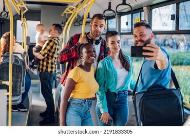 Multiracial smiling group of friends standing in a bus and using smartphone to take a selfie while riding together. Diverse passengers enjoying city ride and taking picture. Public transport. - Powered by Shutterstock