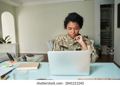 Multiracial soldier woman wearing military uniform looking at the laptop screen