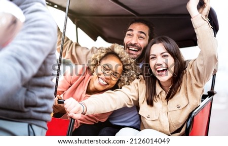 Multiracial students cheering on rickshaw at travel location - Life style concept with guys and girls having fun together - College mates riding around the city after school vacations - Bright filter