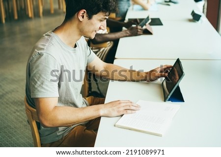 Multiracial students doing research for project inside university library - 