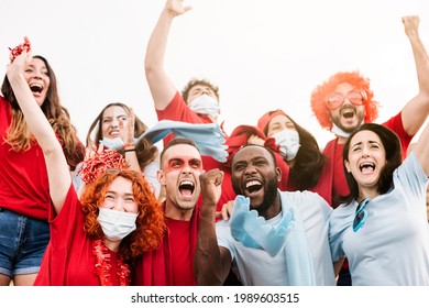 Multiracial Supporters Wearing Protective Face Mask Screaming While Supporting Their Team In The Stadium During The Coronavirus Pandemic - New Normal Live Sports Concept - Focus On Redhead Woman